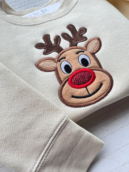 Close-up of Rudolph reindeer appliqué embroidery with brown antlers, beige ears and a sparkling red nose.