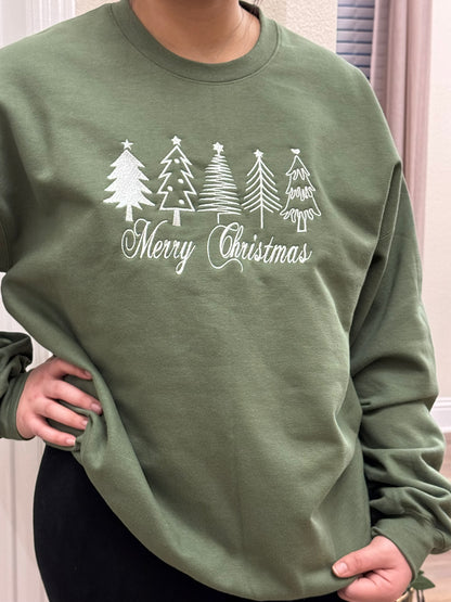 woman wear the heather green sweatshirt with  white thread Merry Christmas embroidery with four festive Christmas trees,