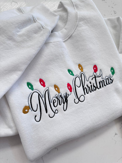 Close up of Christmas lights and Merry Christmas embroidery on white sweatshirt