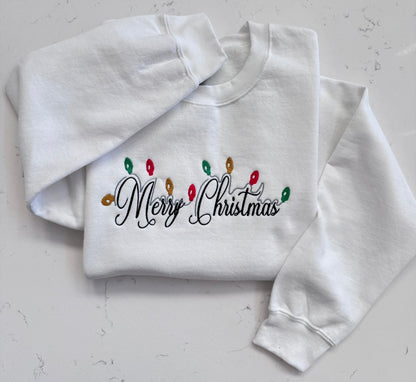 Close up of Christmas lights and Merry Christmas embroidery on white sweatshirt