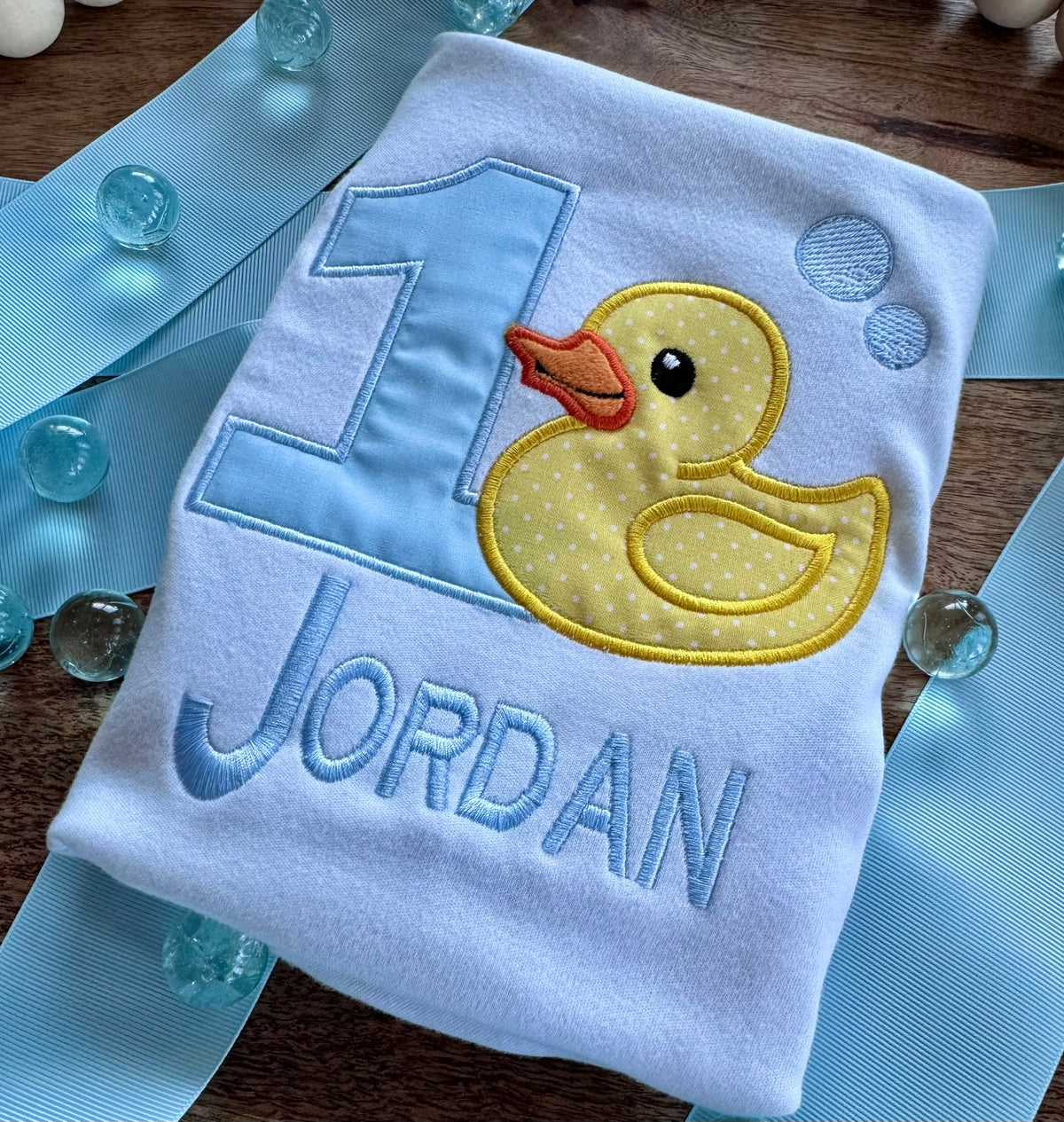 Baby bib with a yellow duck and number 1 design on a white background