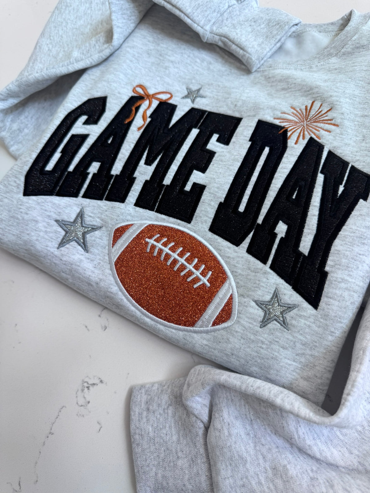 Close-up of glitter football appliqué and embroidered details on Game Day sweatshirt