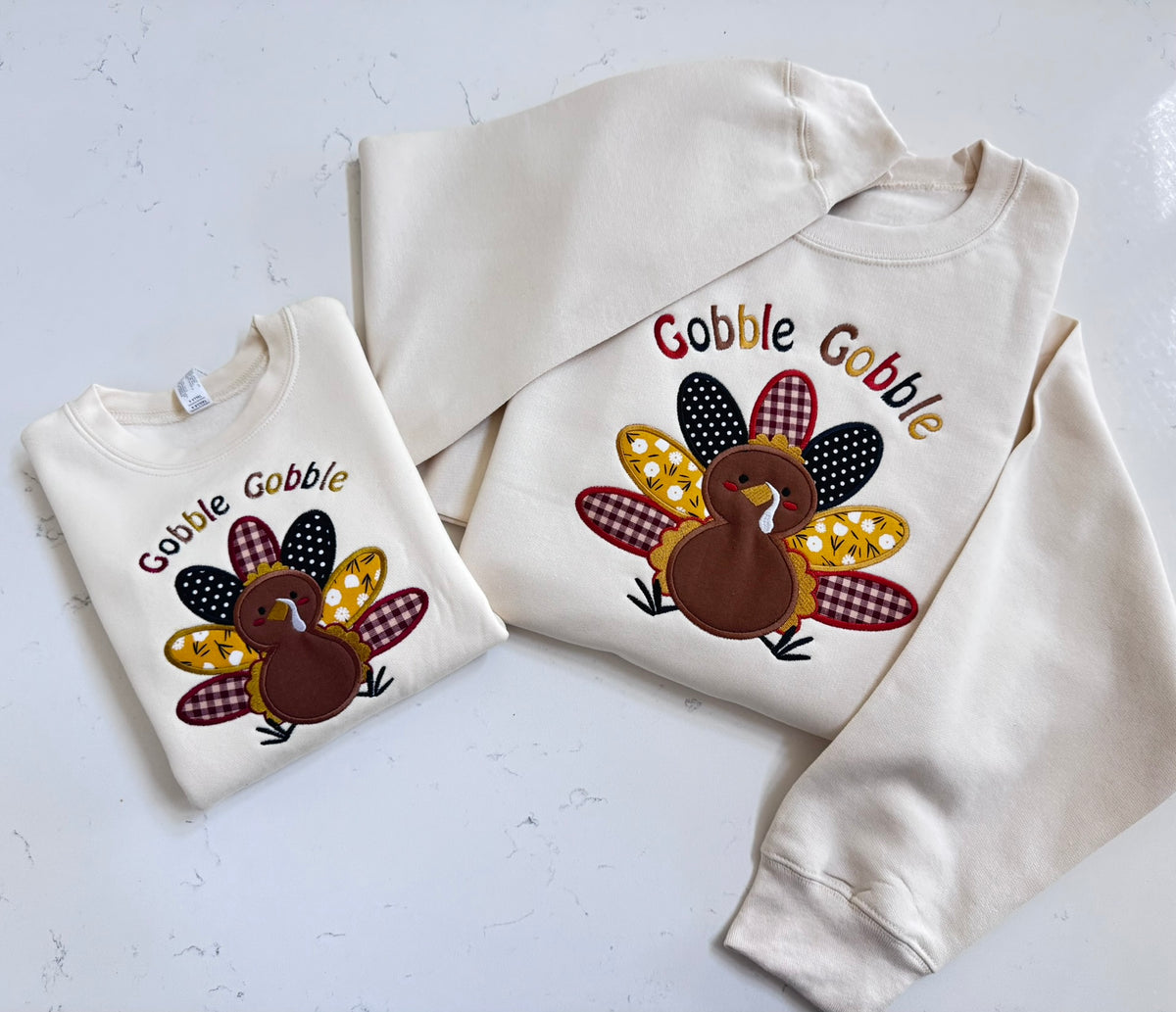 Cream Thanksgiving sweatshirts with colorful embroidered turkey applique, available in matching toddler and adult styles.