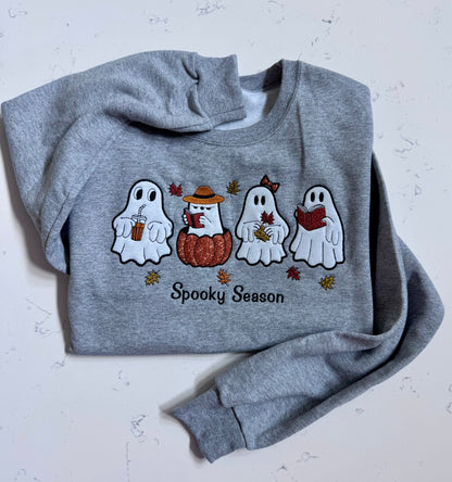 Spooky Season embroidered ghost sweatshirt in heather gray with four ghost characters holding coffee, reading books, and holding fall leaves