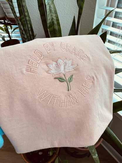 Close-up of Held by Grace embroidery on Christian comfort colors t-shirt