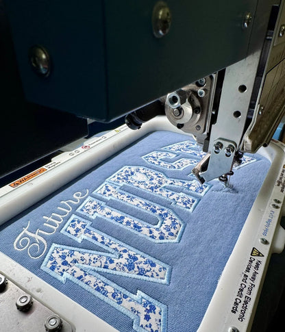 Close-up of Future Nurse floral embroidery detail on blue sweatshirt