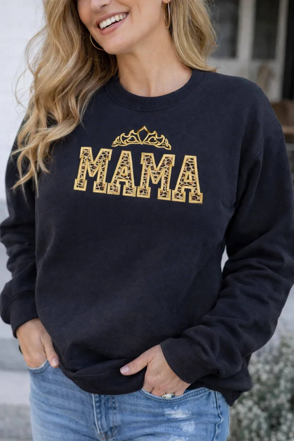 Person wearing a black sweatshirt with 'MAMA' black sweatshirt with leopard embroidered applique with gold crow