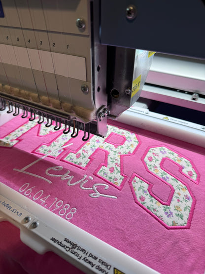 Personalized pink MRS appliqué shirt being professionally embroidered