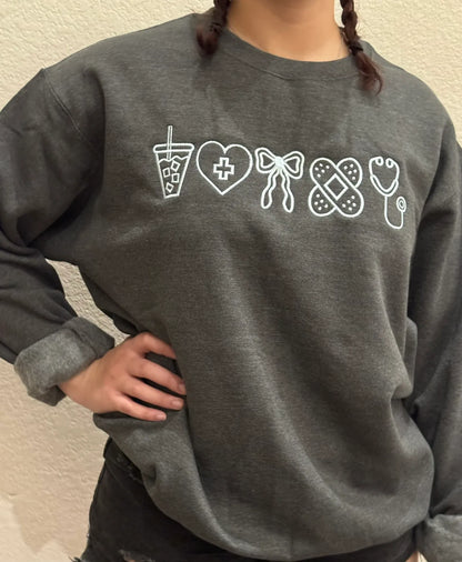 Person wearing a dark gray sweatshirt with white icon for nurse