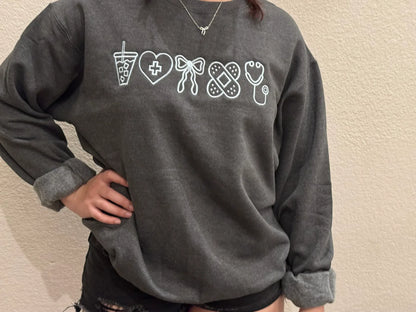 Person wearing a dark gray sweatshirt with white graphic designs for nurse
