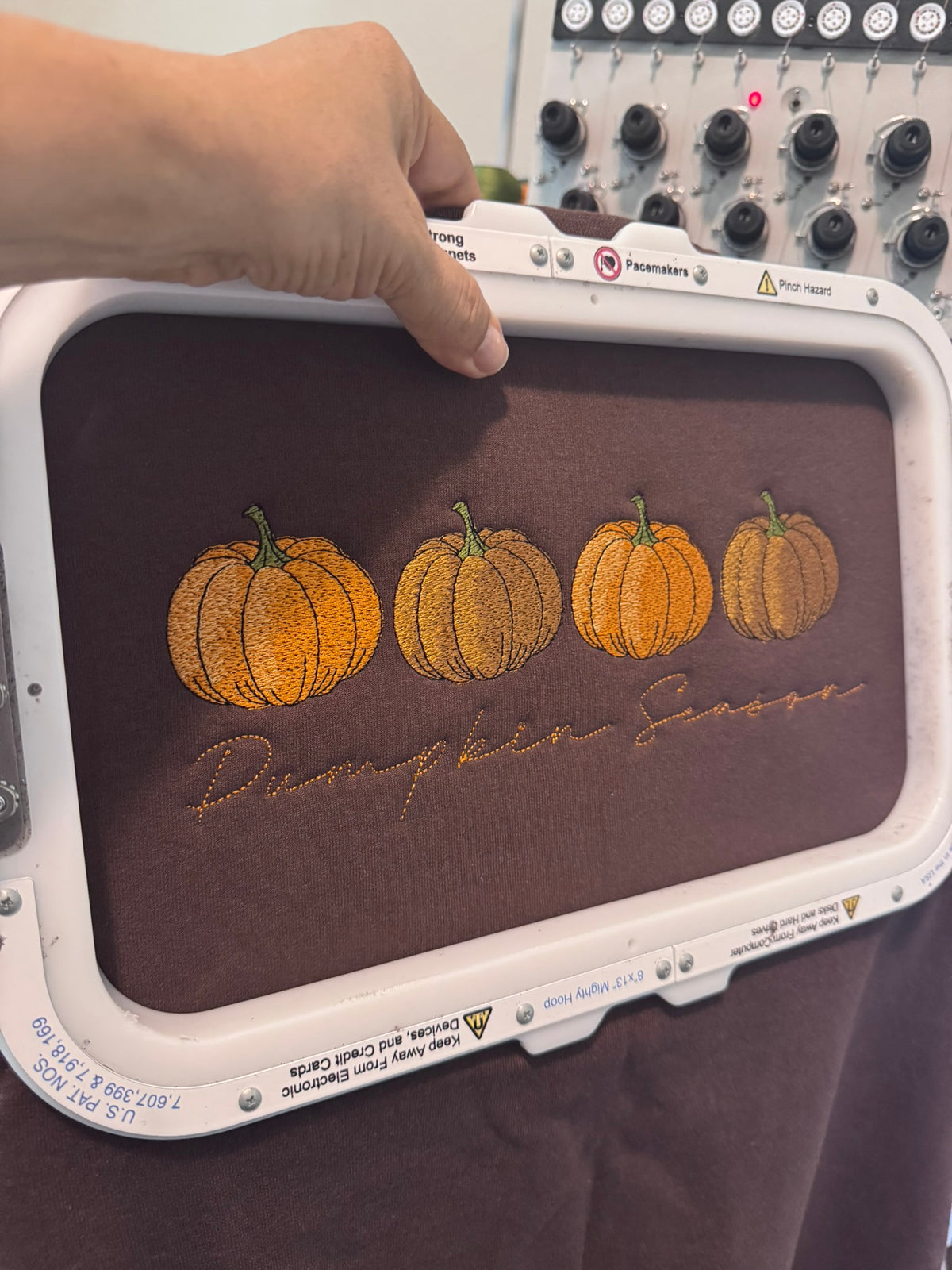 Pumpkin Season design being professionally embroidered with four autumn pumpkins