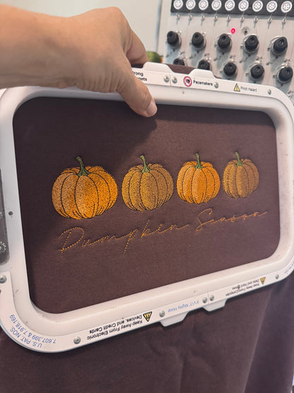 Pumpkin Season design being professionally embroidered with four autumn pumpkins