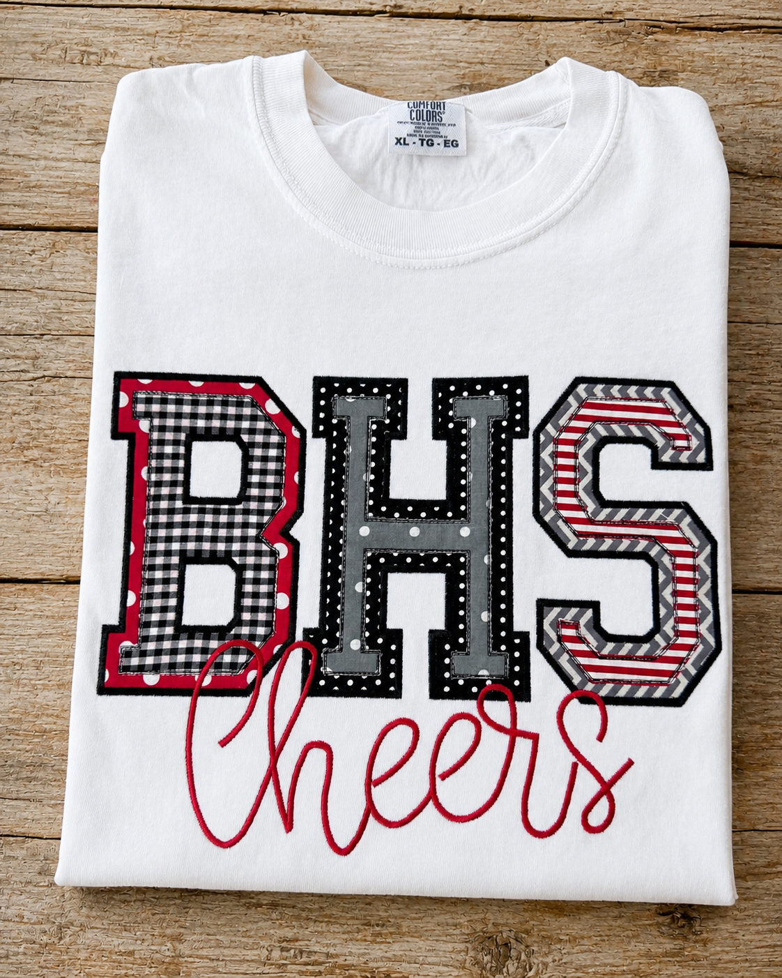 White Comfort Colors custom school initials applique shirt with BHS design and Cheers embroidered in red.