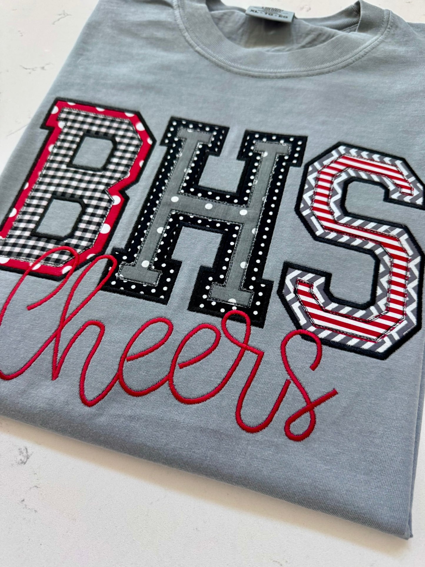 Folded custom BHS school spirit applique shirt in red, black, white and gray with Cheers embroidery.