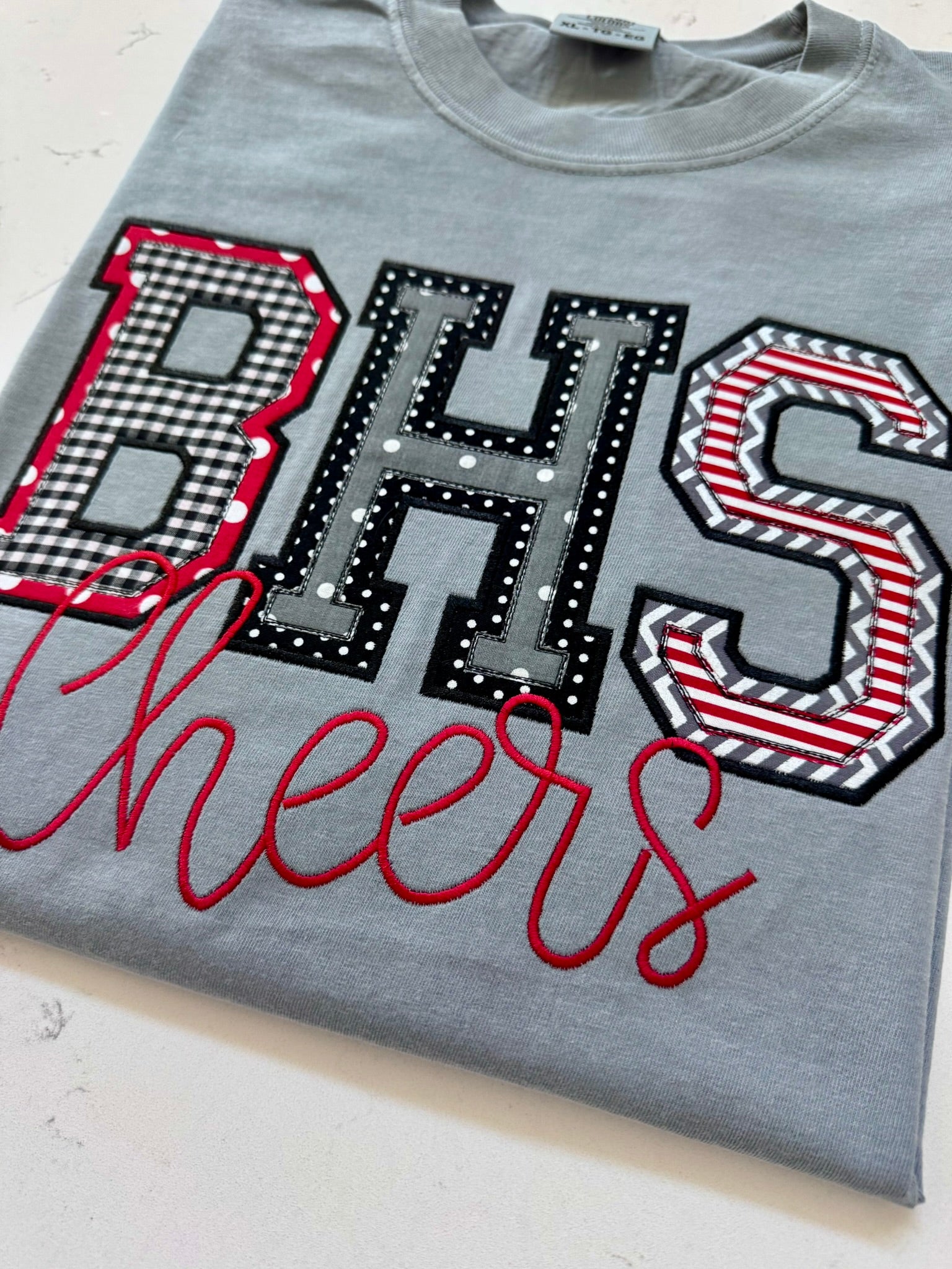 Folded custom BHS school spirit applique shirt in red, black, white and gray with Cheers embroidery.