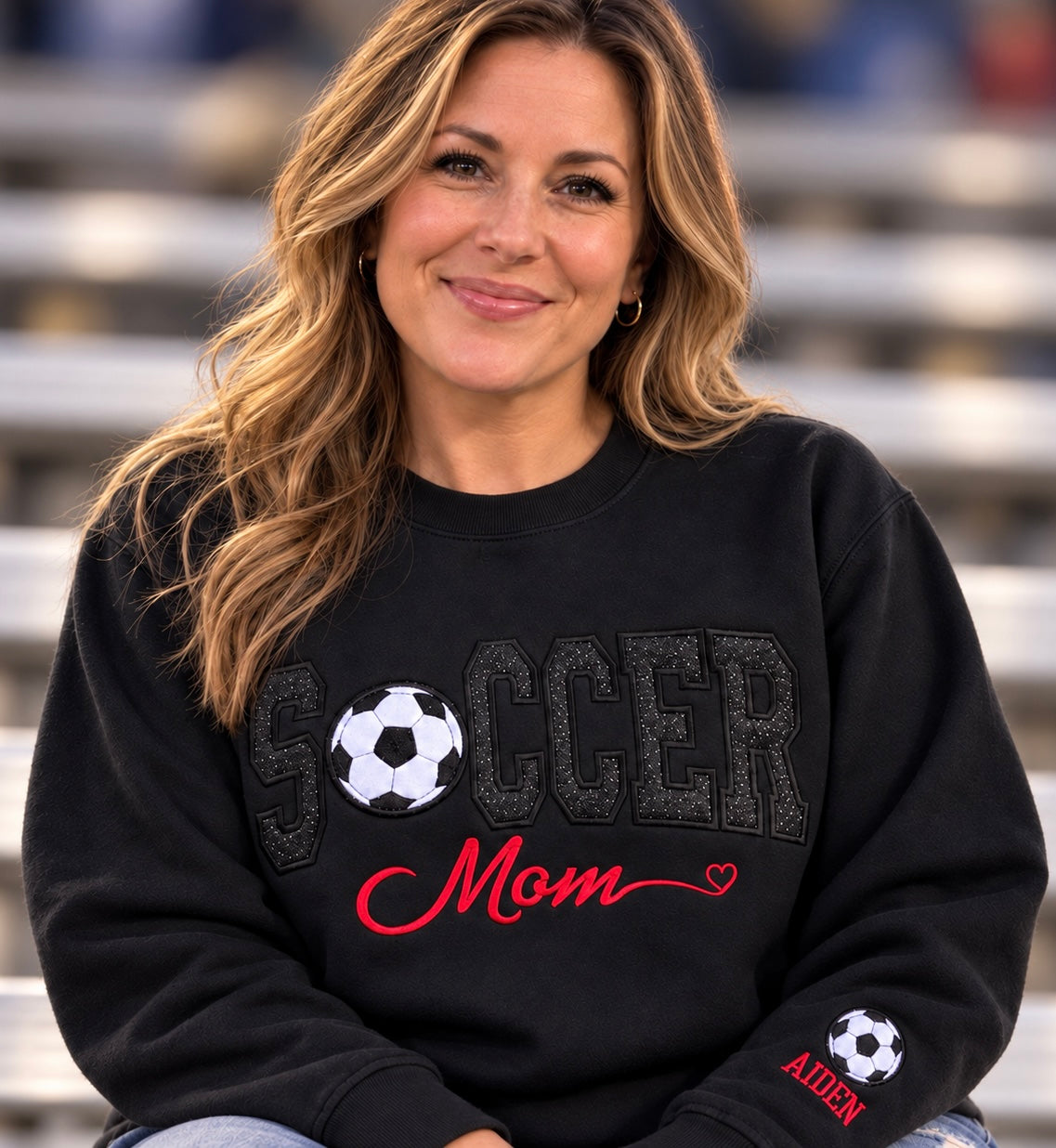 Woman wearing a black Soccer Mom sweatshirt with red custom embroidery