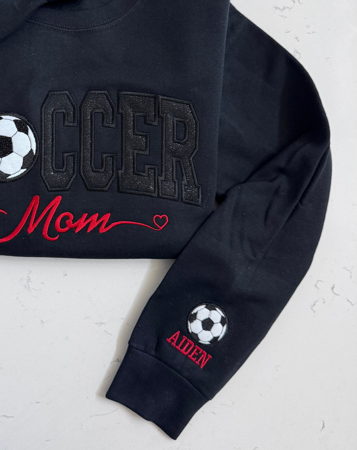 Close-up of black sparkle SOCCER appliqué with embroidered soccer ball