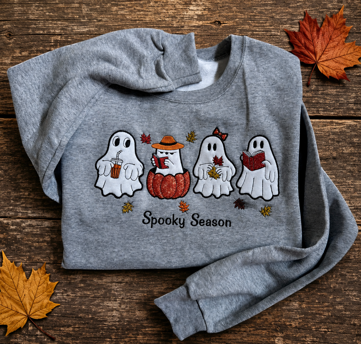Folded gray Halloween sweatshirt featuring four embroidered ghosts and a pumpkin