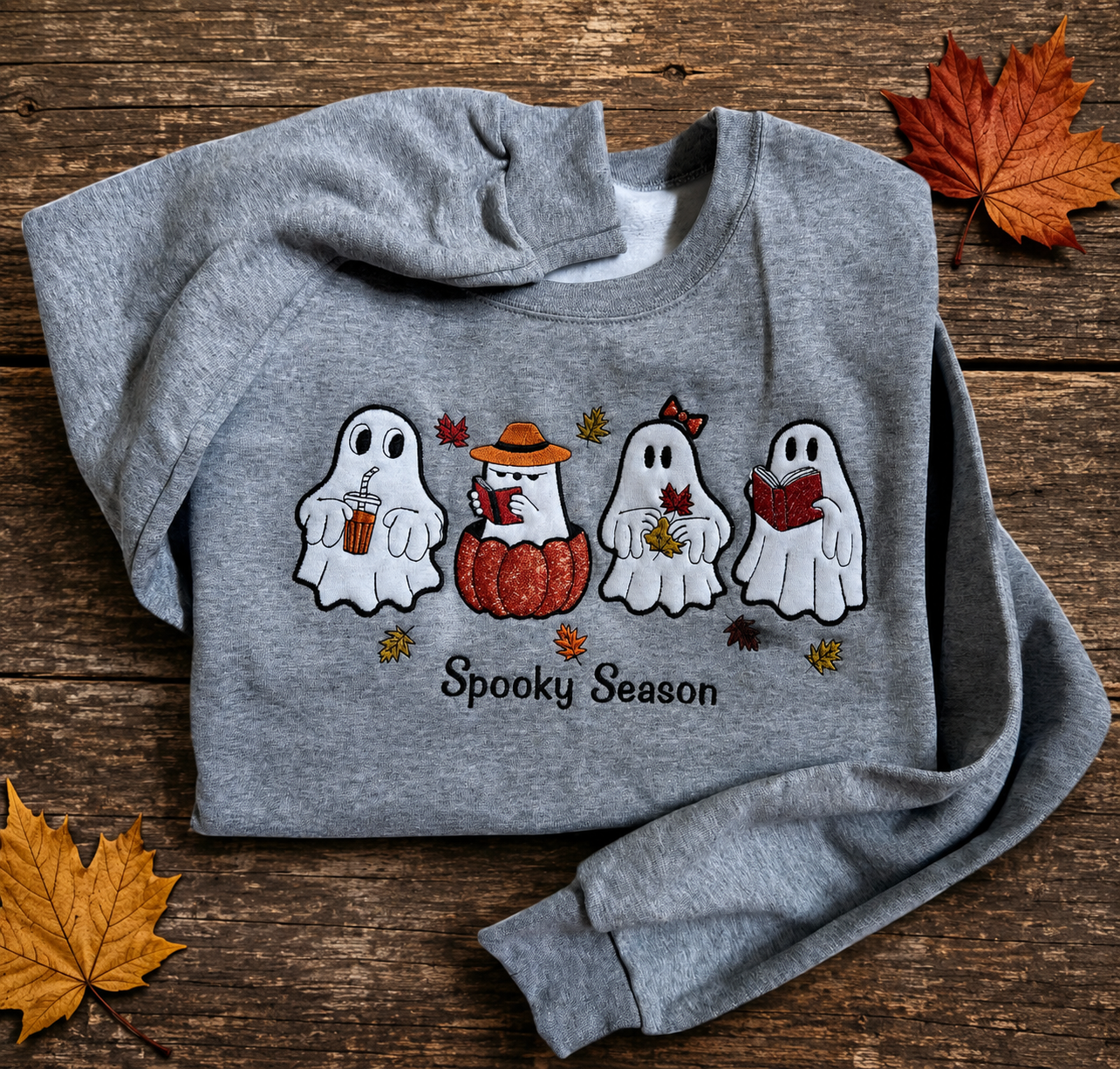 Folded gray Halloween sweatshirt featuring four embroidered ghosts and a pumpkin