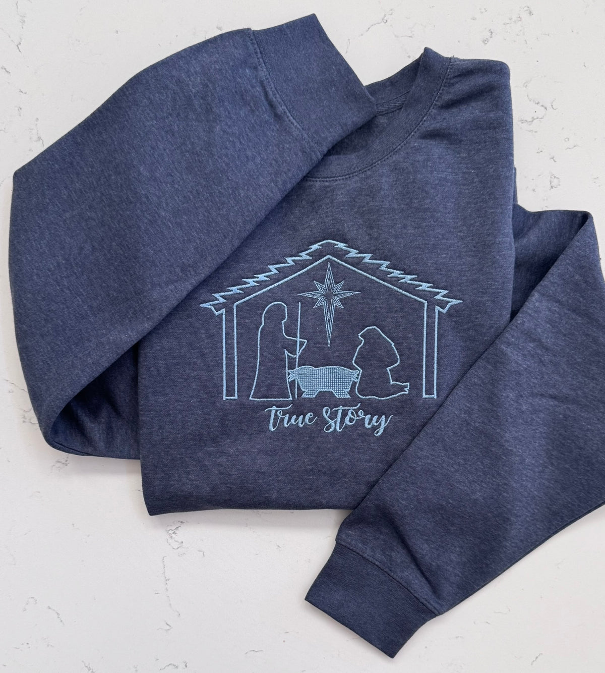 Vintage heather navy Christian Christmas sweatshirt with tonal embroidered nativity scene and True Story lettering.