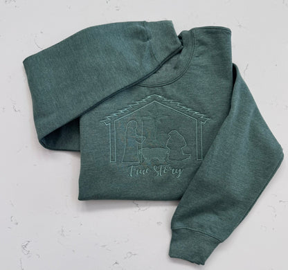 Heather dark green and vintage heather navy sweatshirts featuring the embroidered True Story nativity design.