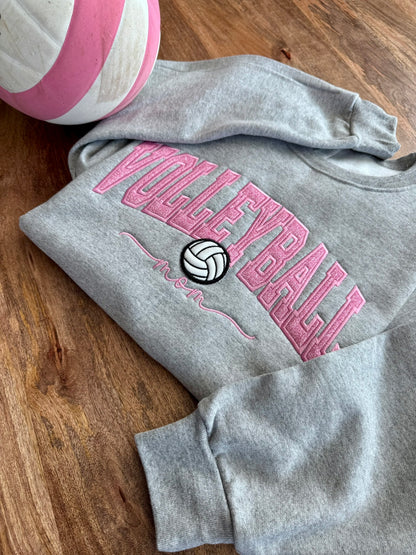 Gray embroidered volleyball sweatshirt displayed beside a pink and white volleyball