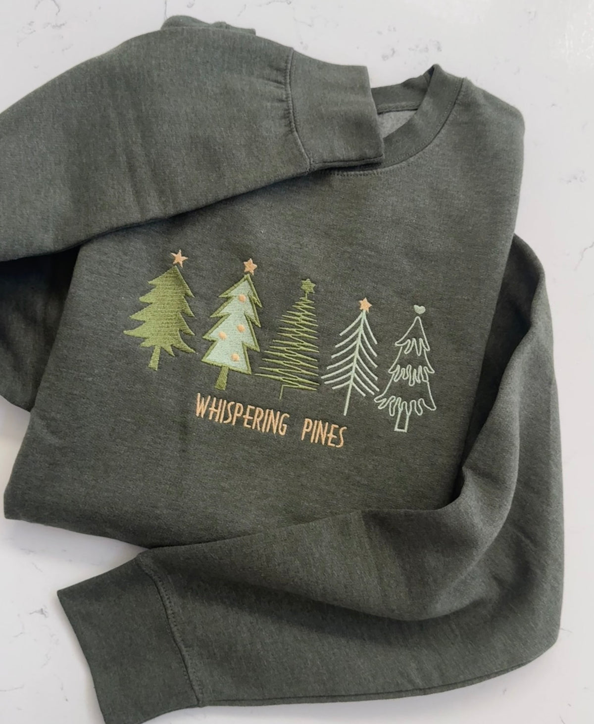 Whispering Pines embroidered winter sweatshirt featuring five evergreen tree designs
