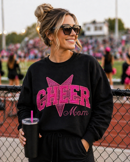 Woman wearing a black 'CHEER Mom' sweatshirt at a sports event.