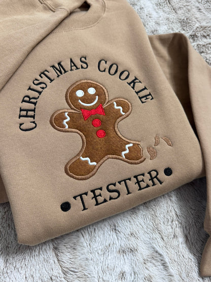 Close-up of gingerbread cookie appliqué and Christmas Cookie Tester embroidery on brown sweatshirt