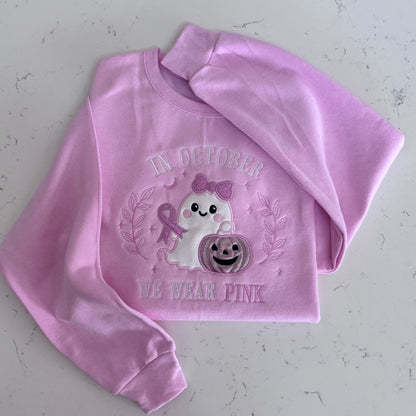 Folded pink sweatshirt featuring the In October We Wear Pink ghost design
